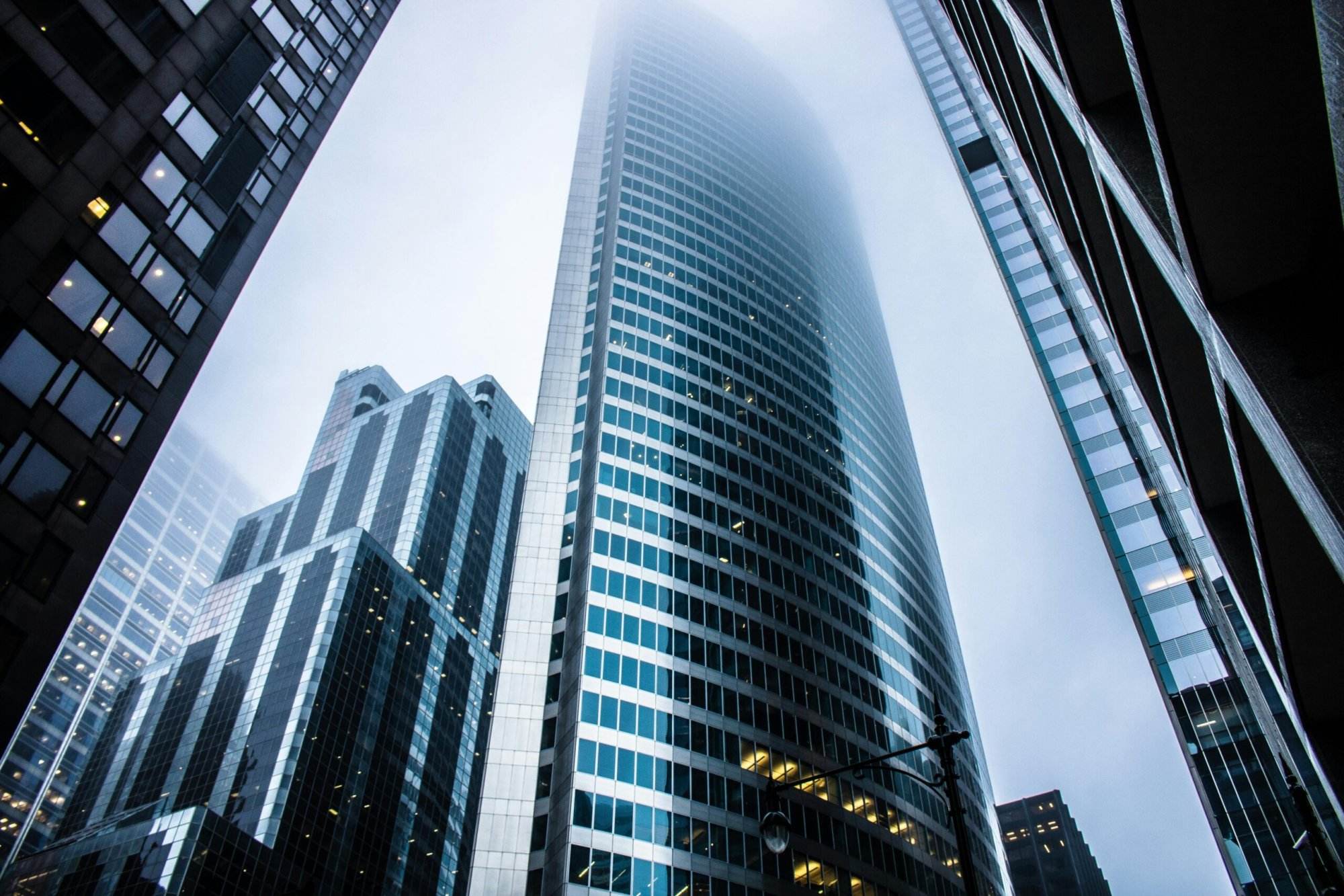 Modern skyscrapers pierce a foggy sky, showcasing impressive architecture and urban development.