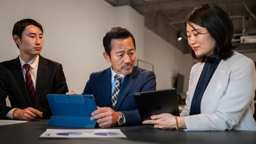 Three businesspeople review documents for an AFSL licence application, ensuring Australian financial services compliance.