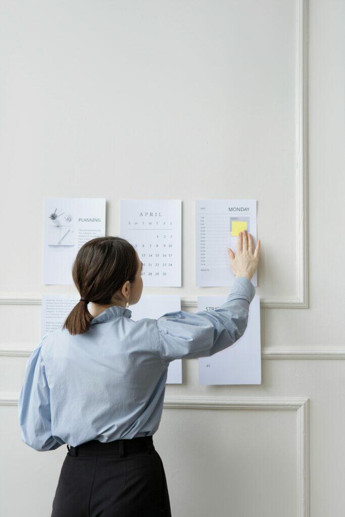 Woman organizing April calendar and schedule, planning tasks for AFSL compliance.