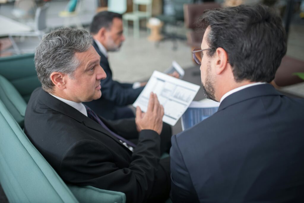 Three businessmen reviewing financial documents, discussing AFSL compliance.