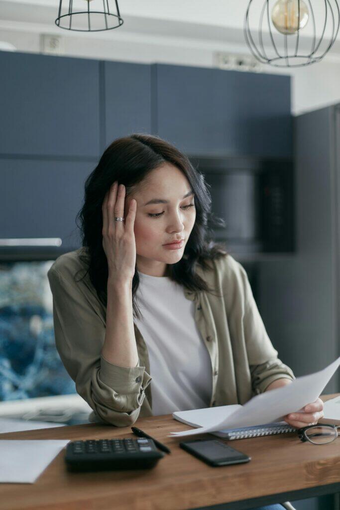 Concerned woman reviewing documents at desk, possibly related to ACL responsible manager qualifications.