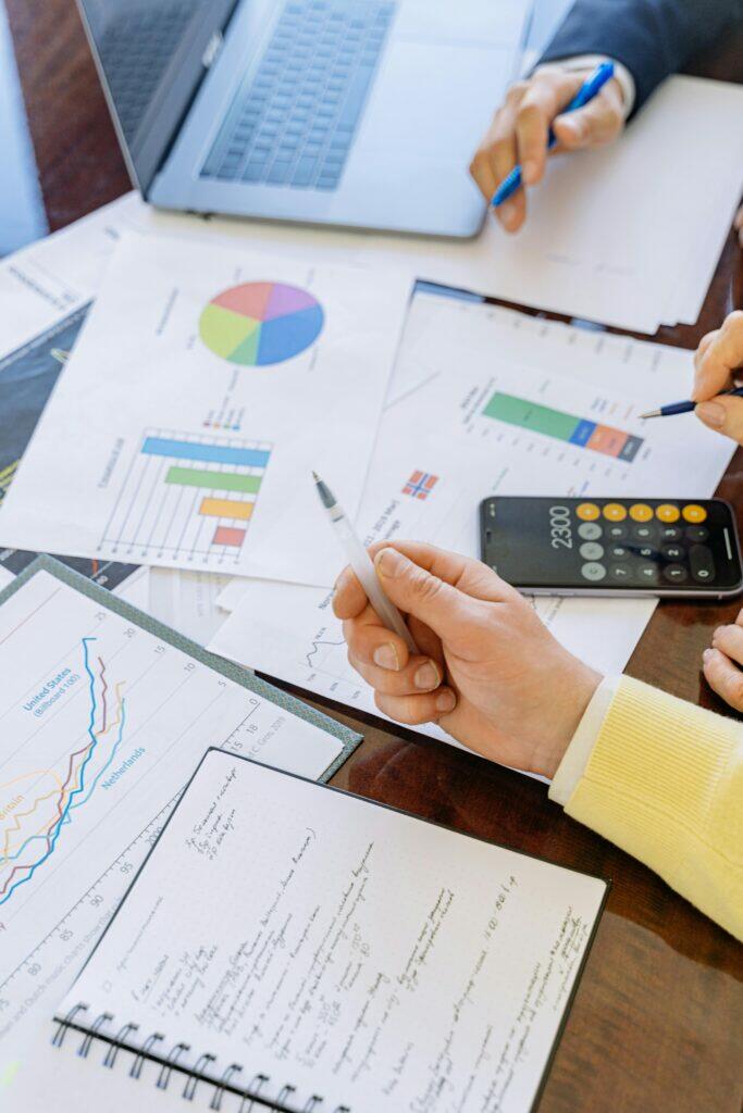 Close-up of hands reviewing financial documents, charts, and calculator; relevant to Australian credit license obligations.