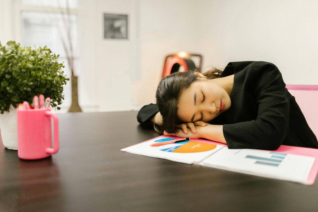 Person asleep at a desk, representing AFSL inactivity that could result in ASIC cancellation and AFSL issues.