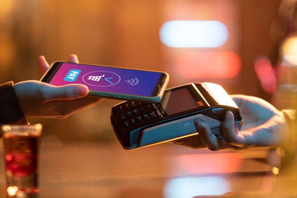 Paying with phone at a bar. Digital payment with a mobile device at a point-of-sale terminal.