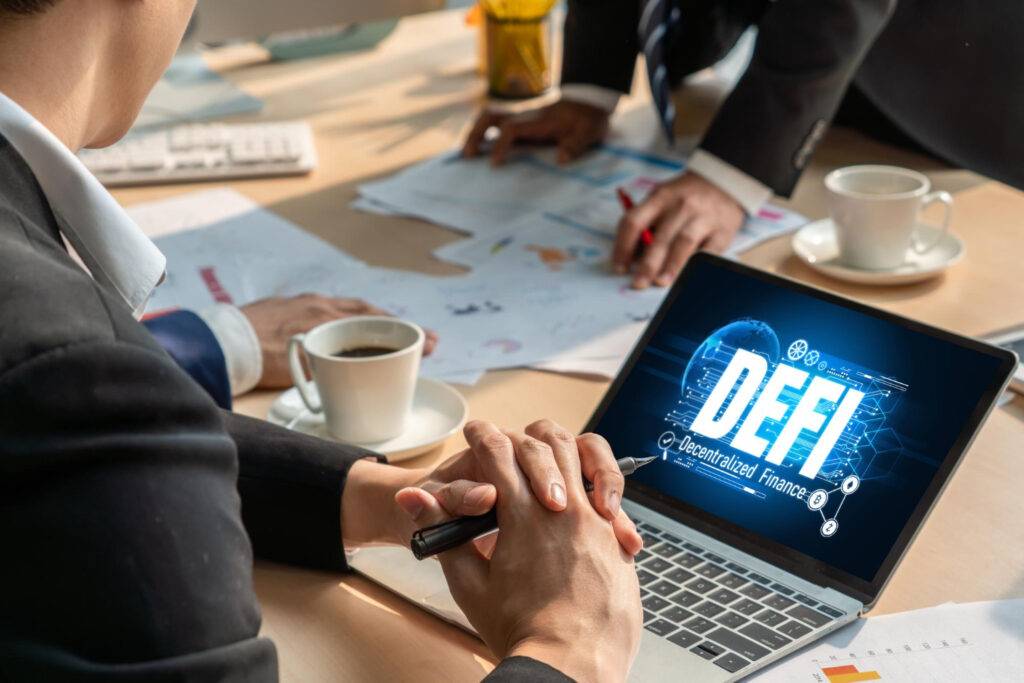 DeFi concept on laptop screen with business professionals discussing tokenisation of real-world assets.