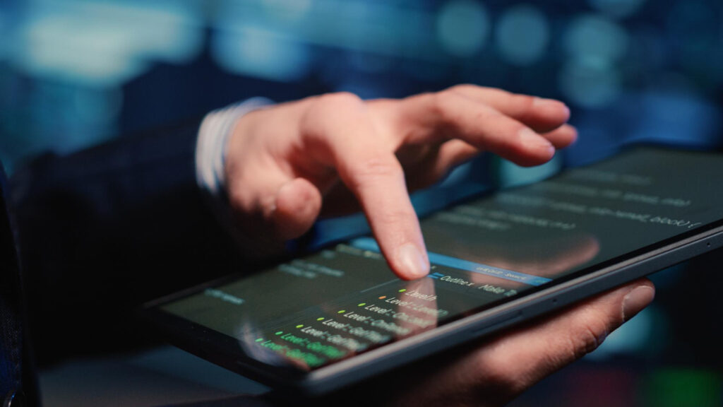 Hand using a tablet displaying code outlines, possibly related to staking-as-a-service.